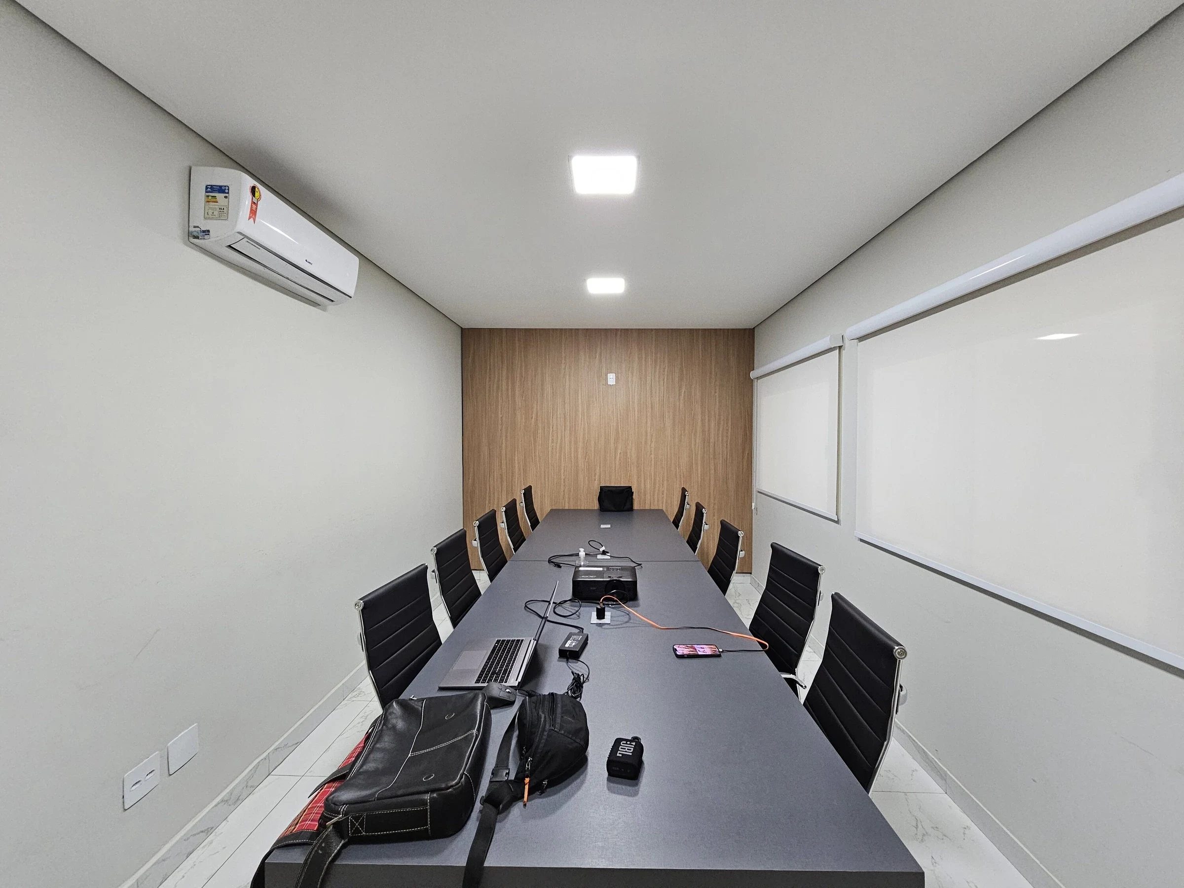 Equipamentos e computador organizados sobre mesa em sala de reunião