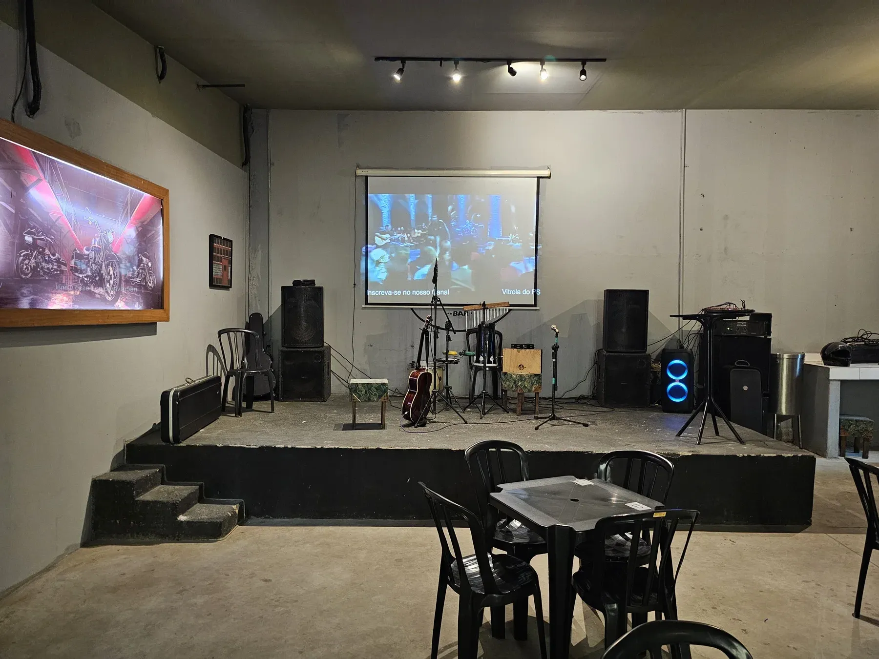 Palco, instrumentos e área de mesas de um bar